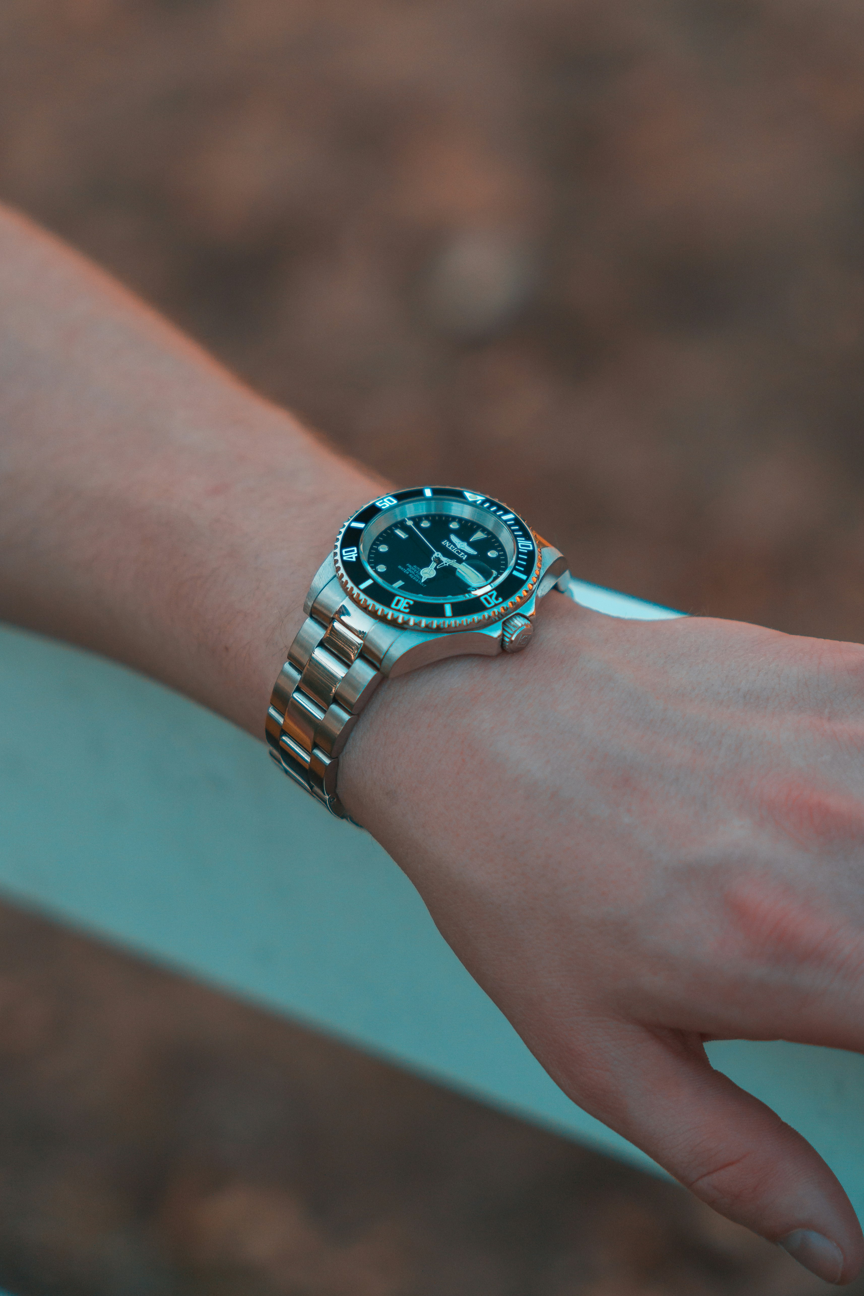 person wearing silver link bracelet round chronograph watch